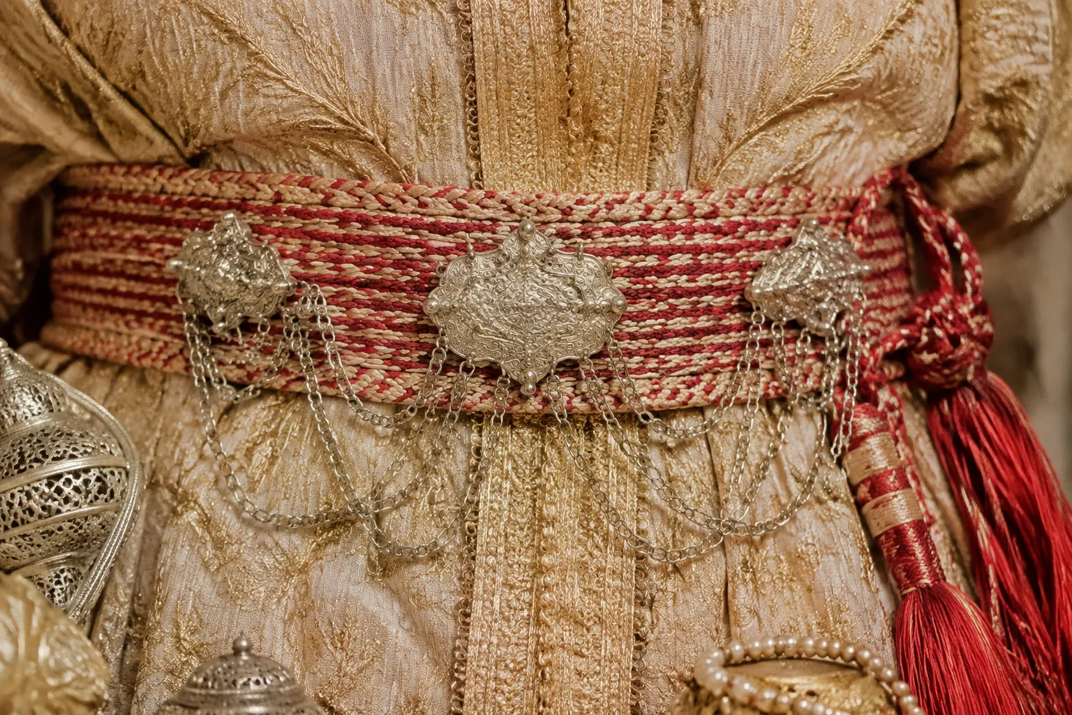 Close view of a Moroccan bridal belt mdamma over embroidered fabric
